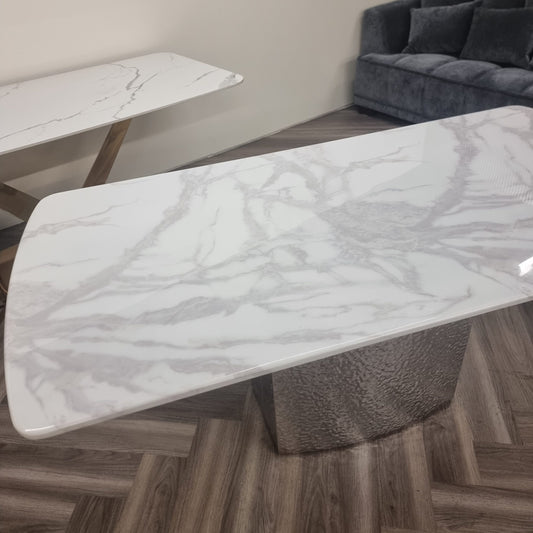 White marble dining table with gray veining and a textured pedestal base