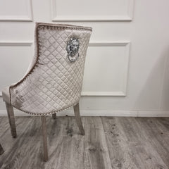 Dining chair back with quilted beige velvet, chrome lion-head accent and metal legs