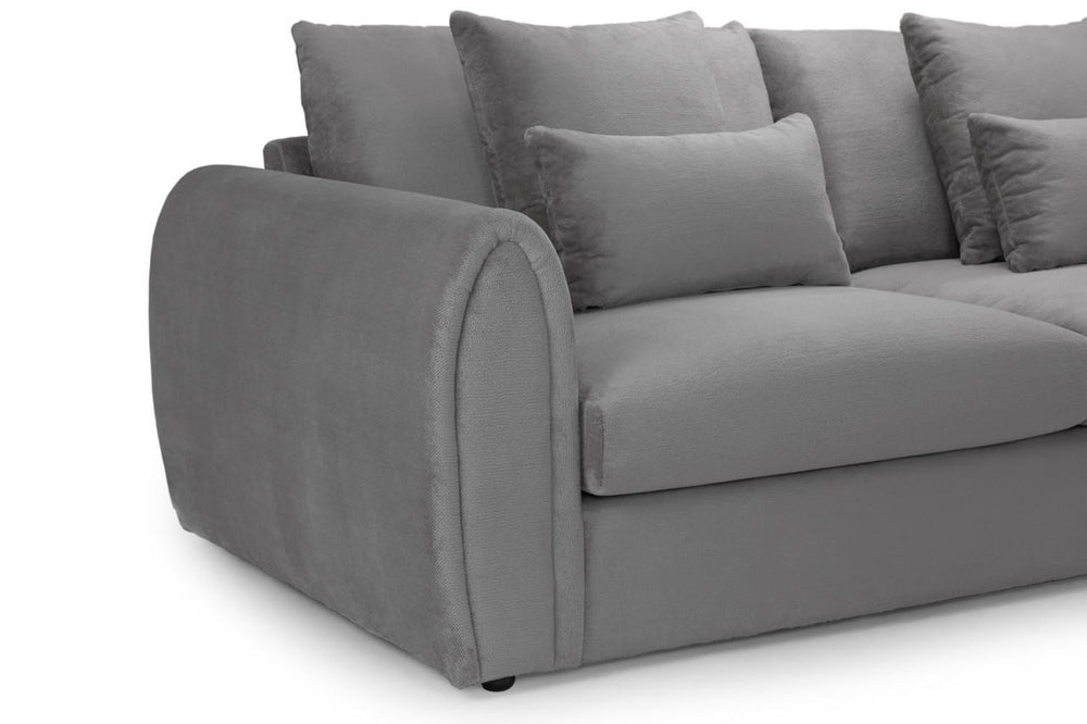 Close-up of the gray sofa's rounded arm, seat cushion, and loose scatter pillows