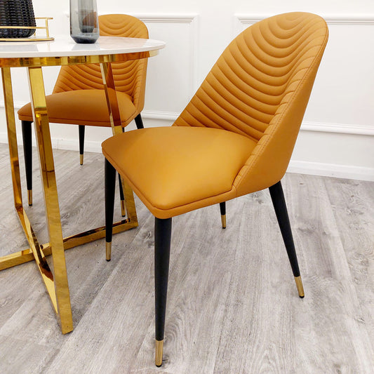 Tan leather dining chair with a quilted curved back and tapered black legs