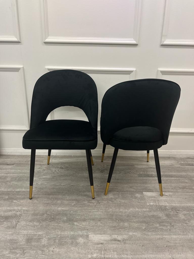 Two black velvet dining chairs showing cutout and solid curved back designs