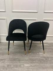 Two black velvet dining chairs showing cutout and solid curved back designs