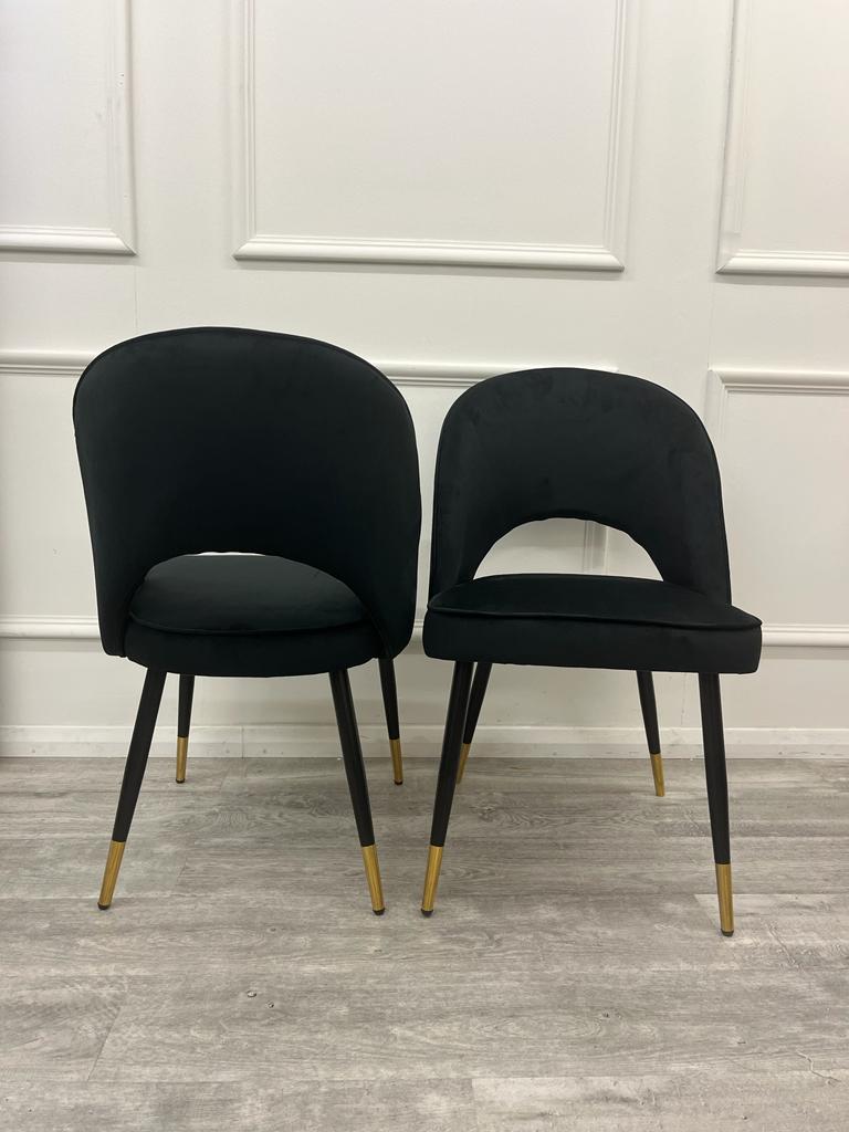 Set of two black velvet dining chairs with curved backs and gold-tipped legs