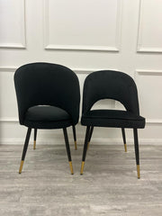 Set of two black velvet dining chairs with curved backs and gold-tipped legs
