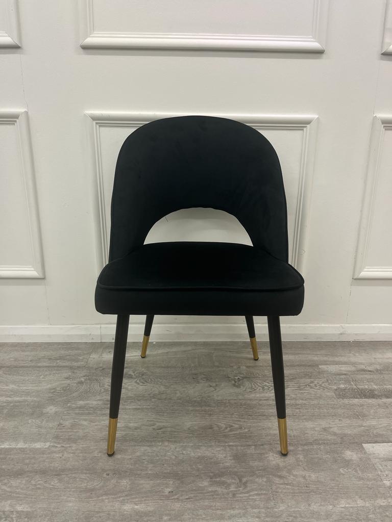 Black velvet dining chair with a cutout back and gold-tipped legs