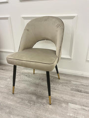 Champagne velvet dining chair shown at an angle, with a curved back and padded seat
