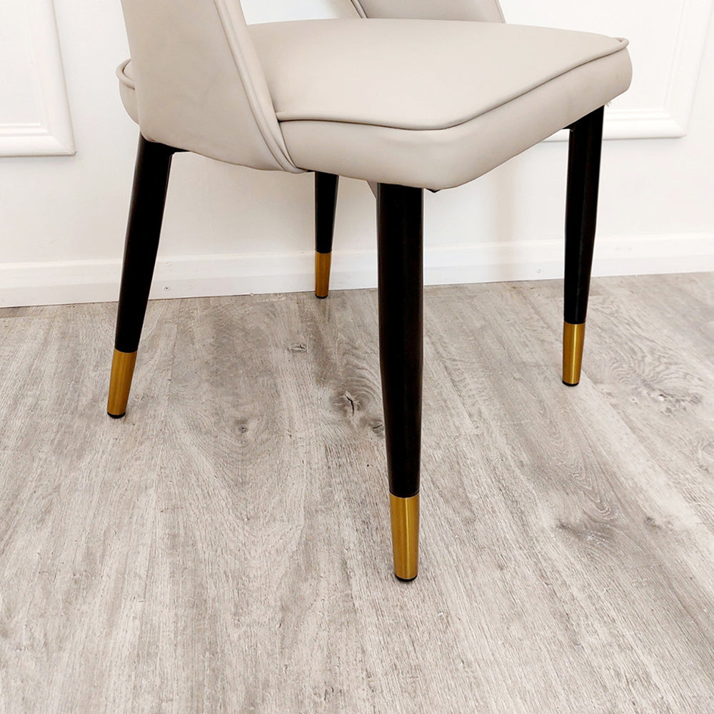 Beige leather dining chair detail showing tapered black legs with gold-tone tips