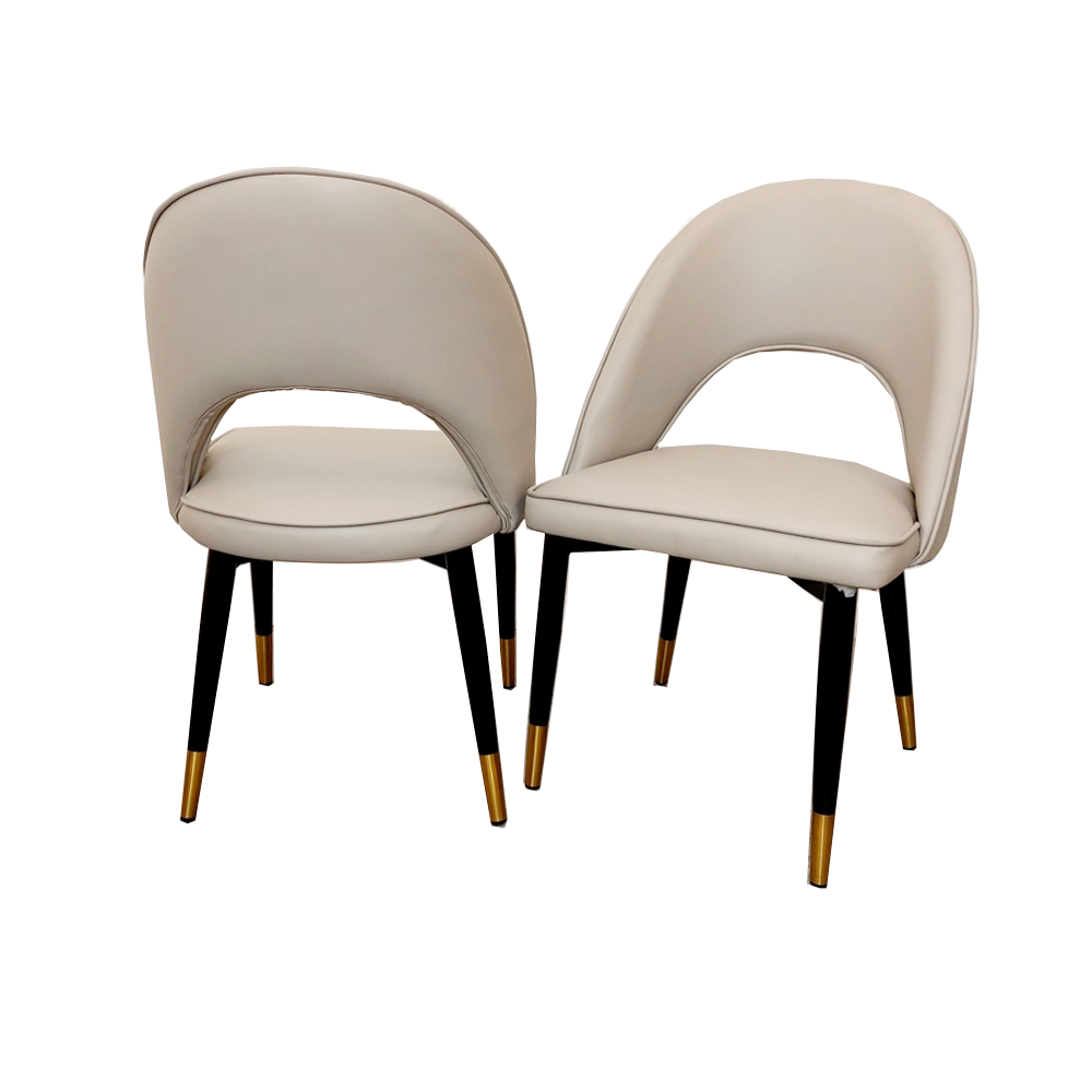 Set of two beige leather dining chairs with curved backs and black legs with gold-tone tips