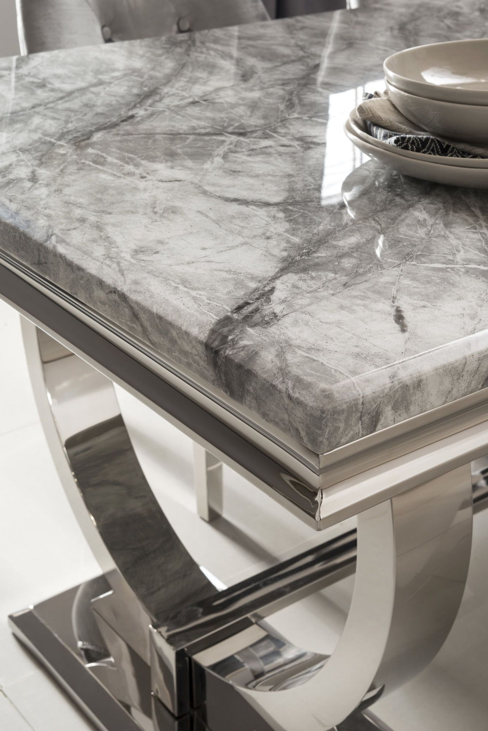 Close view of the Arriana table's gray veined stone top and polished metal base