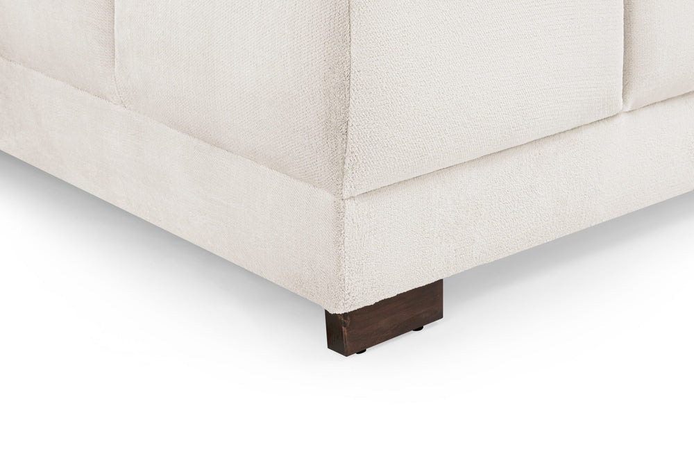 Azzuro sofa detail showing cream upholstery, stitched seams and a dark wooden foot