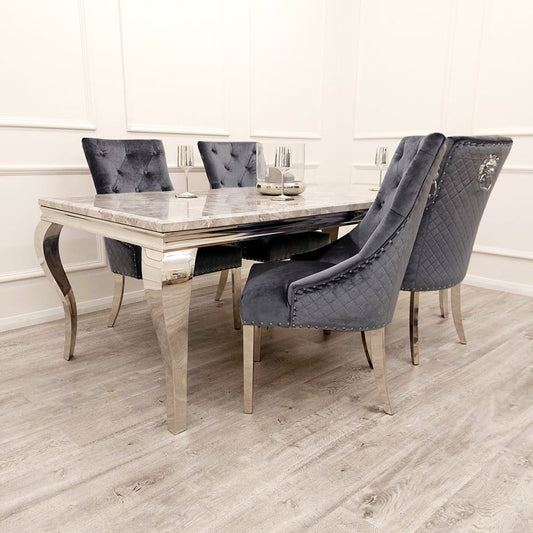 Dark gray velvet dining chair with tufted upholstery and chrome legs, shown at a dining table