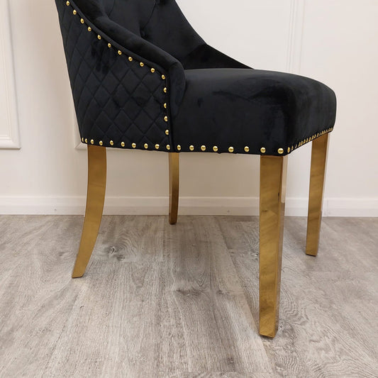 Black velvet dining chair with quilted sides, gold nailhead trim, and gold legs