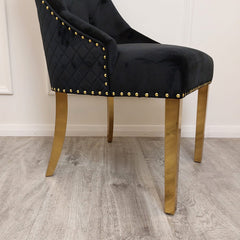 Black velvet dining chair with quilted sides, gold nailhead trim, and gold legs