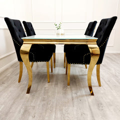 Black velvet dining chairs with gold legs arranged around a dining table