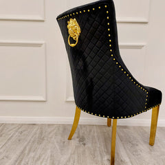 Black velvet dining chair with a diamond-quilted back, gold trim, and a decorative ring