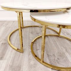 Gold metal frames and circular bases of nested end tables with white stone tops