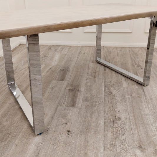 Freya dining table side view showing its light wood top and chrome U-shaped legs