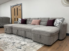 Gray sofa bed with wide chaise seats and decorative pillows