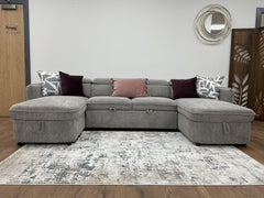 Capri U-shaped sofa bed with gray upholstery and decorative throw pillows