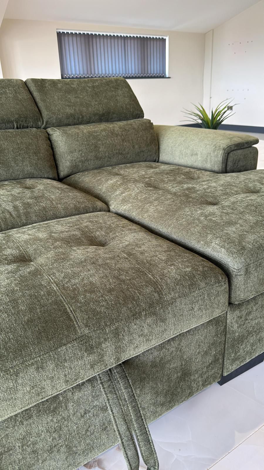 Close-up of green sofa bed upholstery, tufted seat, and fabric pull strap