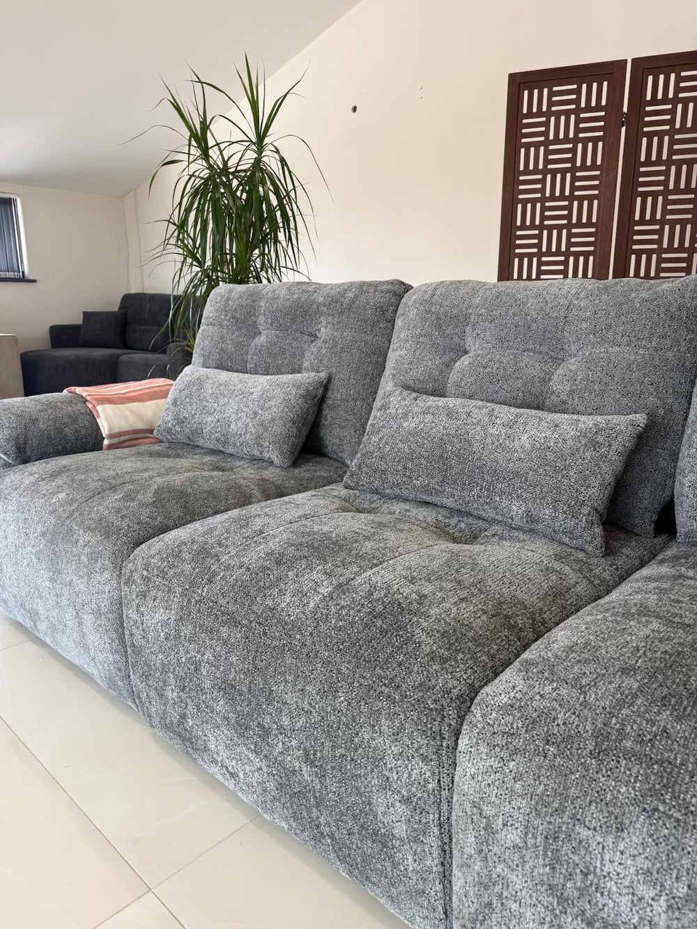 Close view of the sofa bed's gray textured upholstery and tufted back cushions