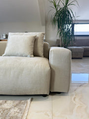 Close-up of the sofa's light gray fabric, padded arm, seat, and cushion