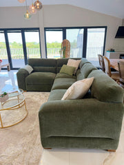 Corner sofa side view showing its chaise, broad armrest, and textured green upholstery