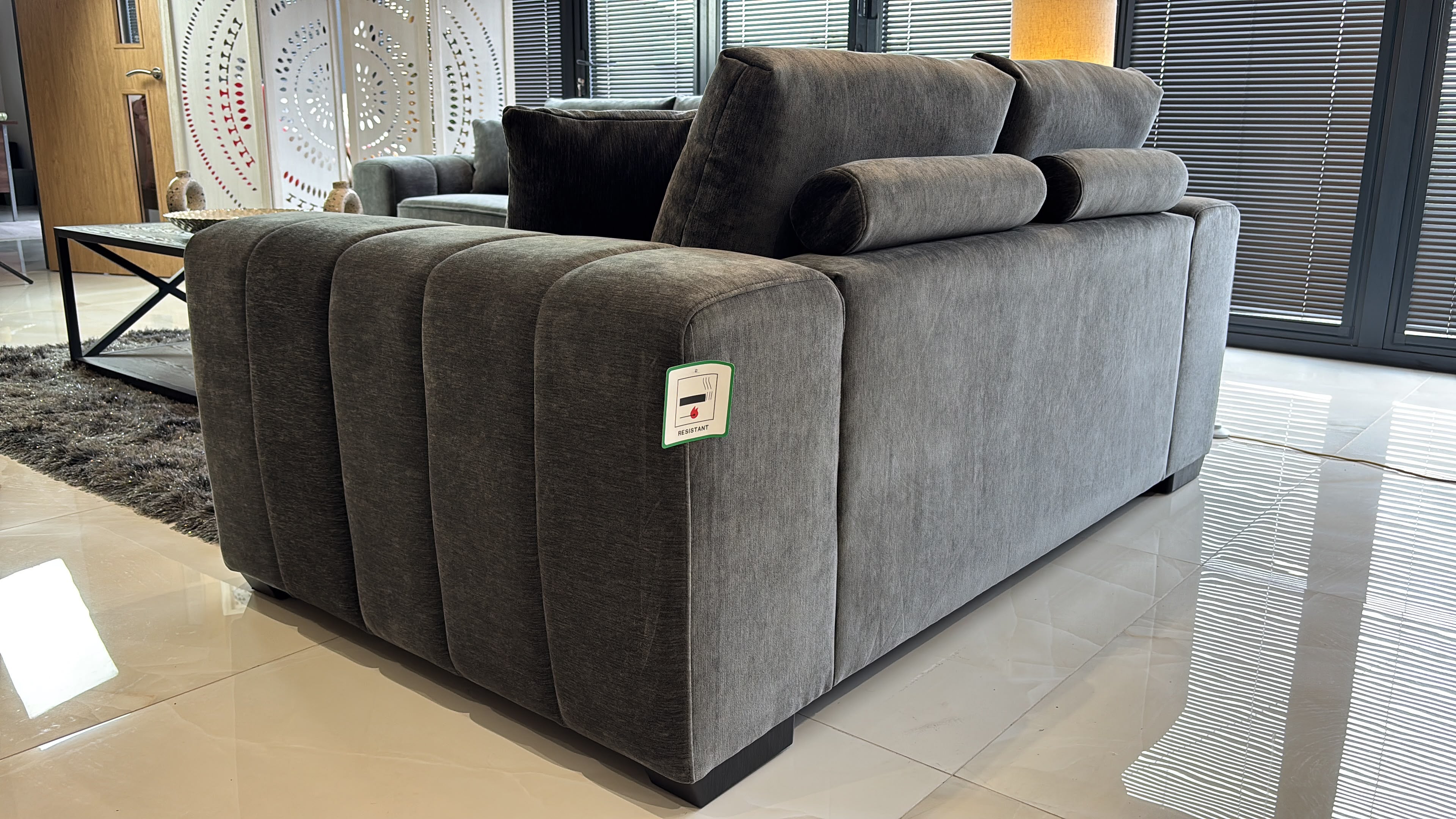 Gray sofa viewed from behind, showing its upholstered back and ribbed arm