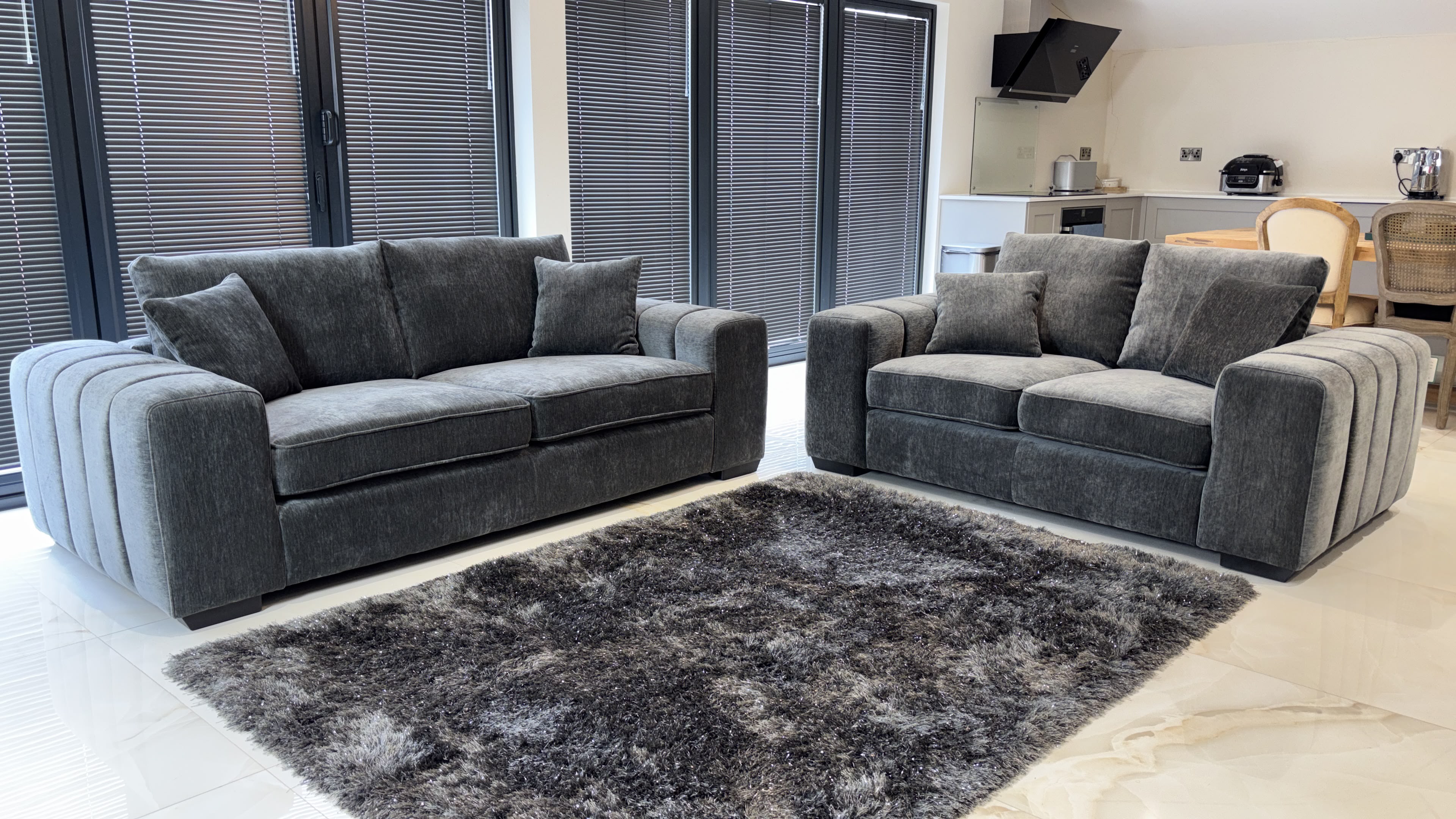 Gray sofa set with two sofas, plush cushions and rounded, ribbed arms