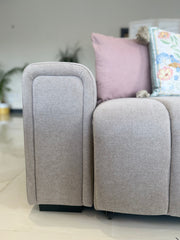 Close-up of the sofa bed's padded armrest and seat cushion in light gray fabric