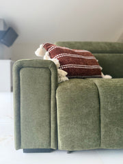 Close-up of the sofa bed's padded olive armrest and textured upholstery