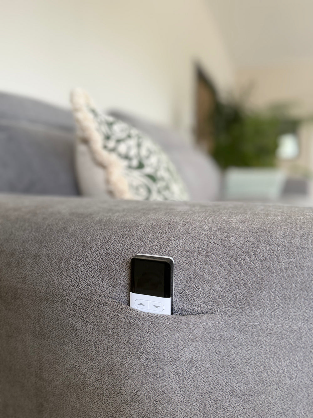 Gray sofa arm with a remote control tucked into its side pocket