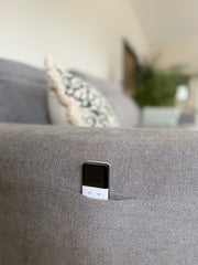 Gray sofa arm with a remote control tucked into its side pocket