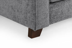 Close-up of a dark wood armchair foot beneath gray fabric upholstery