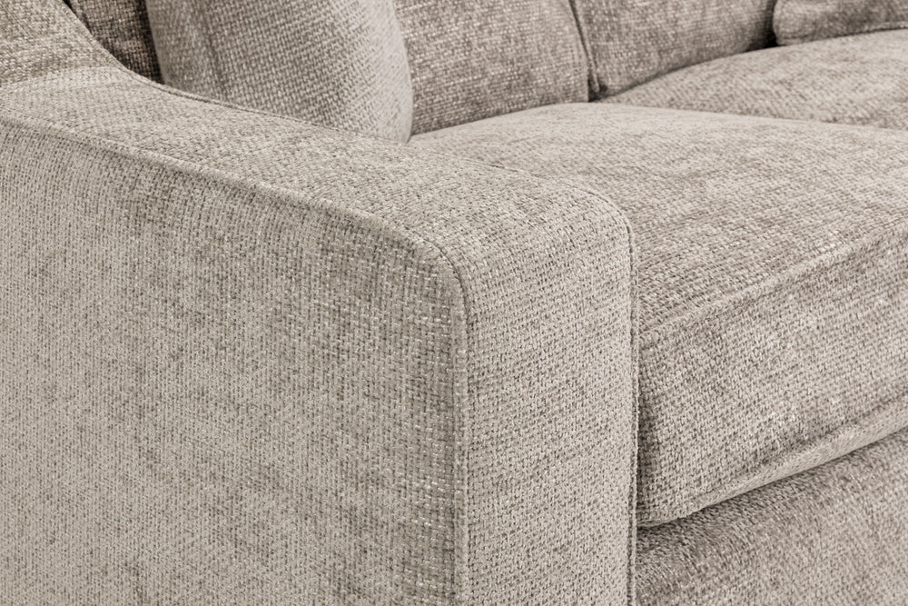 Sofa close-up showing a broad padded arm and seat cushion in textured beige fabric