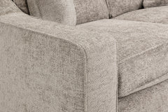 Sofa close-up showing a broad padded arm and seat cushion in textured beige fabric