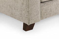 Sofa corner with textured beige upholstery and a dark wooden foot