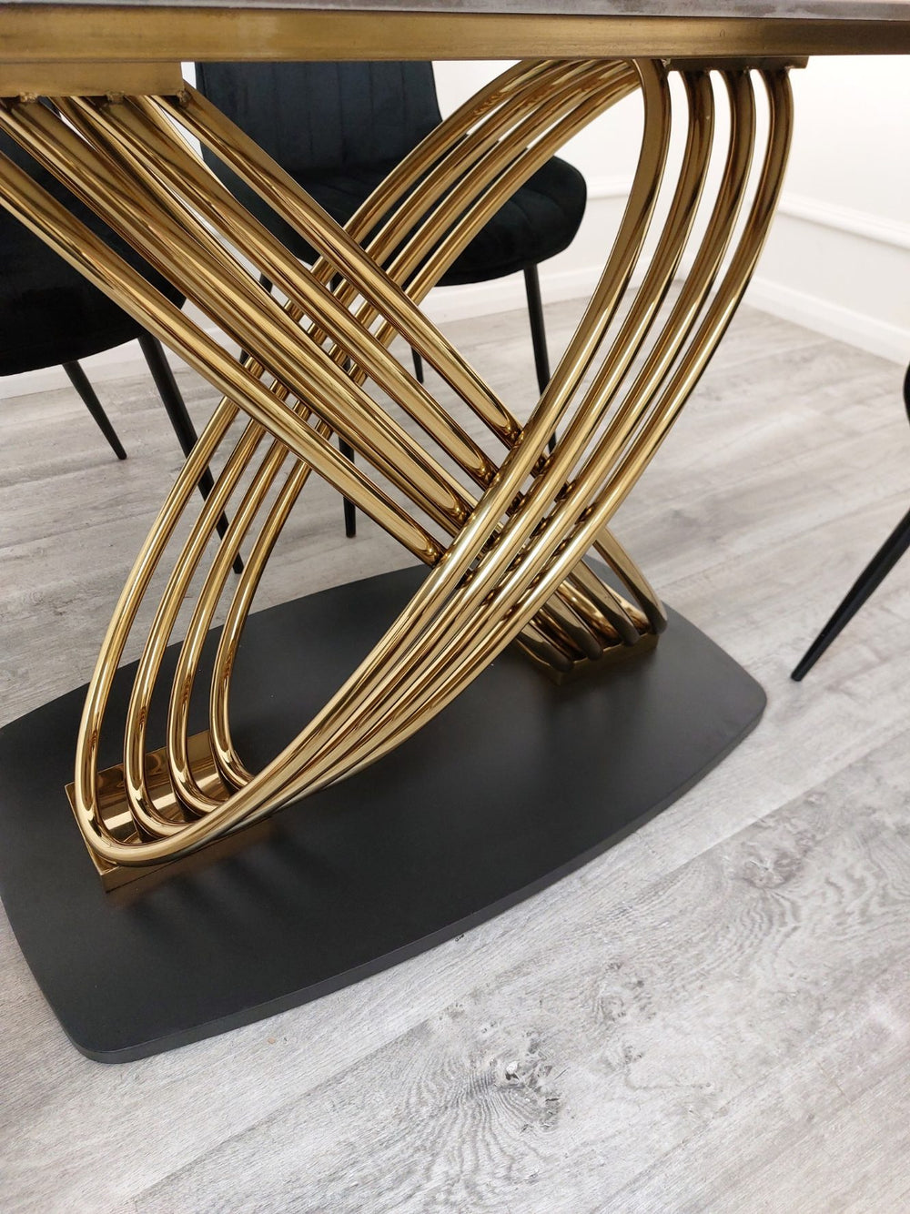 Close view of the dining table's intertwined gold metal supports and dark base