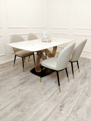 White stone dining table with gold pedestal base surrounded by beige chairs