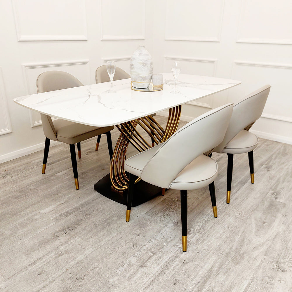 White veined stone dining table with sculptural gold-tone base and rounded corners