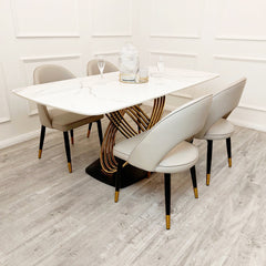 White veined stone dining table with sculptural gold-tone base and rounded corners