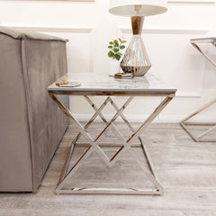 Chrome lamp table beside a sofa, showing its slim stone top and angular base