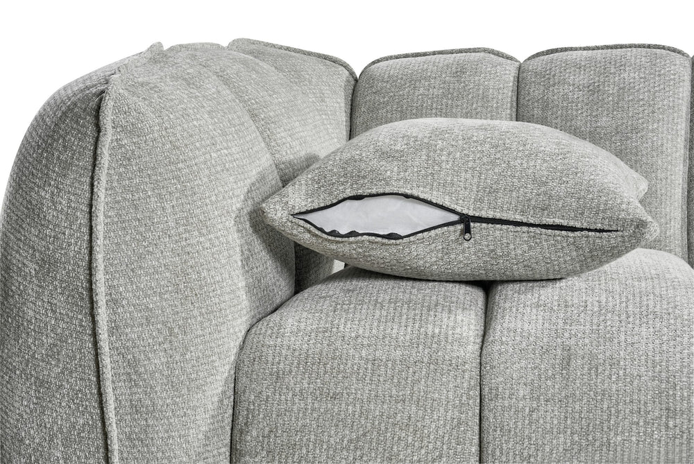 Sofa detail showing a loose cushion with a zippered cover and channel back