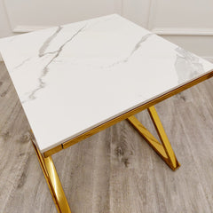 Close view of white veined tabletop and angular gold legs