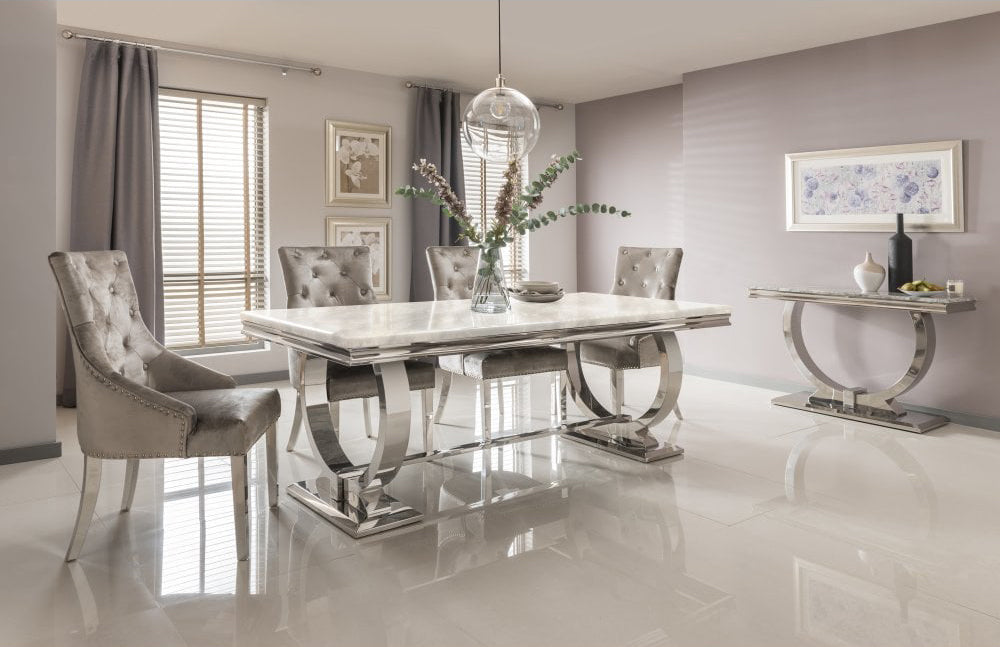 Arriana dining table with a pale stone top and curved polished metal supports