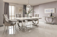 Arriana dining table with a pale stone top and curved polished metal supports