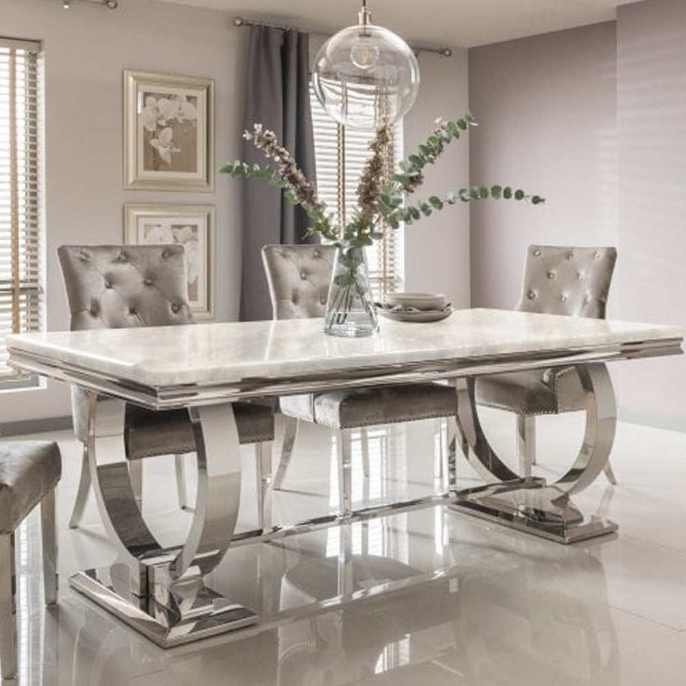 Arriana dining table with a pale veined stone top and polished metal loop base
