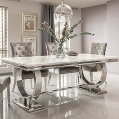 Arriana dining table with a pale veined stone top and polished metal loop base