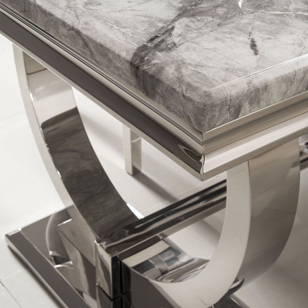 Arriana dining table with gray veined stone top and polished metal base, close-up