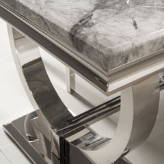 Arriana dining table with gray veined stone top and polished metal base, close-up